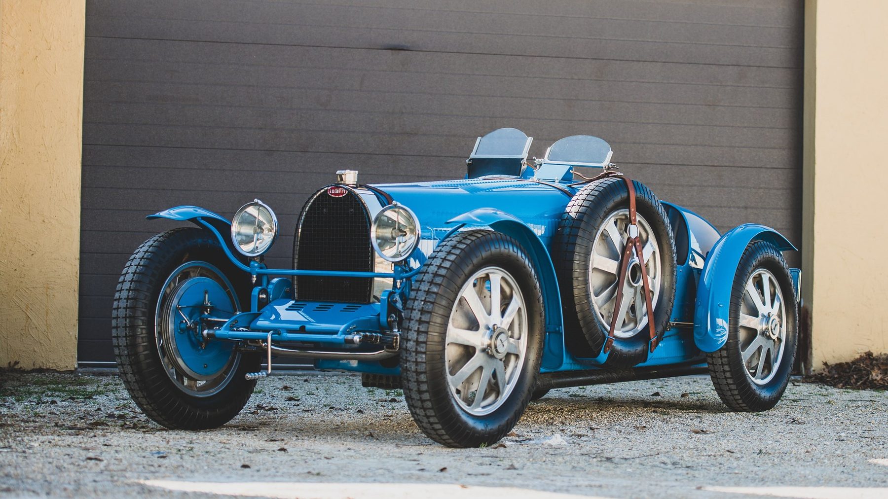 Bugatti Type 35 in Blau, Dreiviertelansicht von vorn, vor einem Werktor
